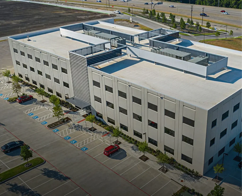 King of Texas completed a new construction roofing project on a modern multi-story commercial building with a white flat roof and rooftop mechanical systems.