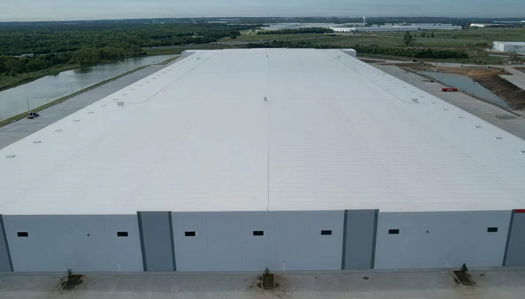 Large commercial warehouse with white flat roof installed by a commercial roofing contractor.