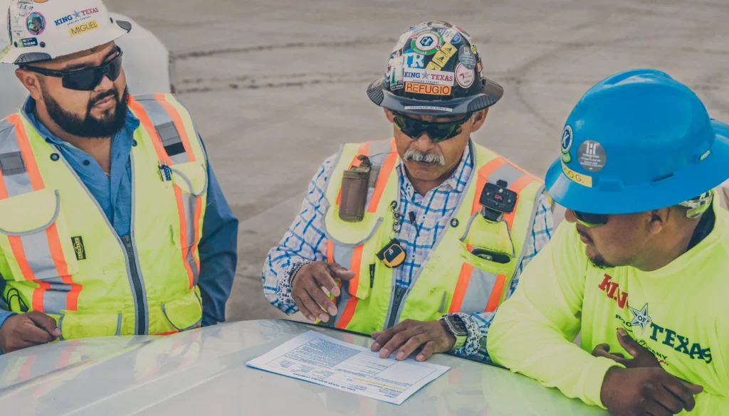 Commercial roofing team reviewing plans and documents on rooftop job site.